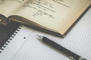 Mathematical study scene with open book, graph paper, and pen for learning and homework.